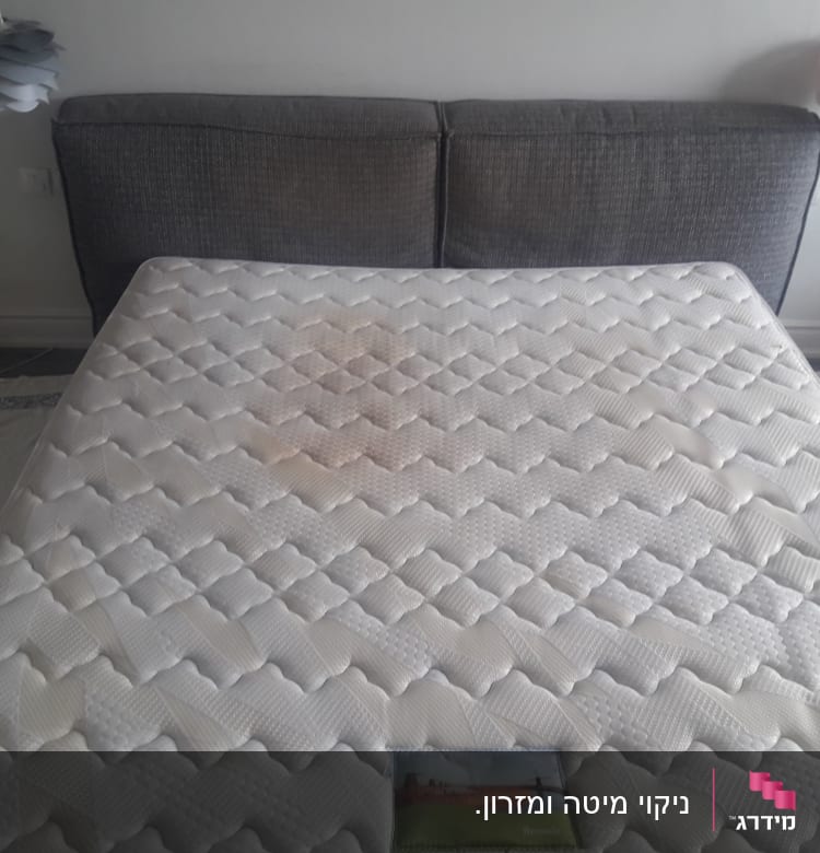 מזרן עם כתם גדול על רקע מיטה אפורה